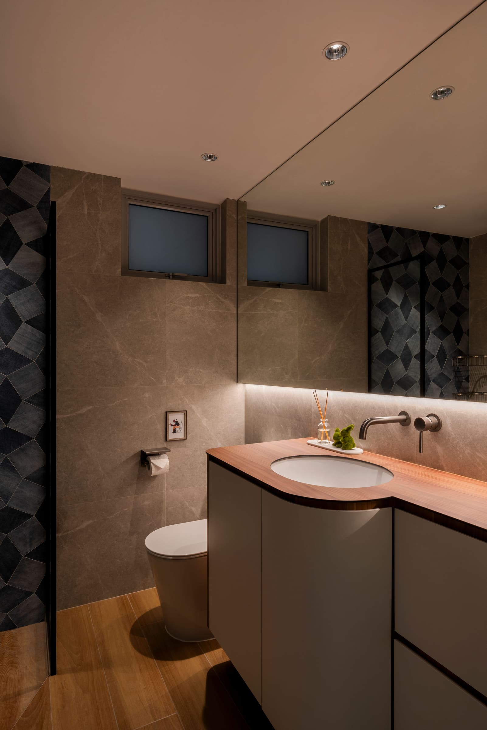 Powder room with a concealed strip under the mirror washing the stone wall and timber vanity top.