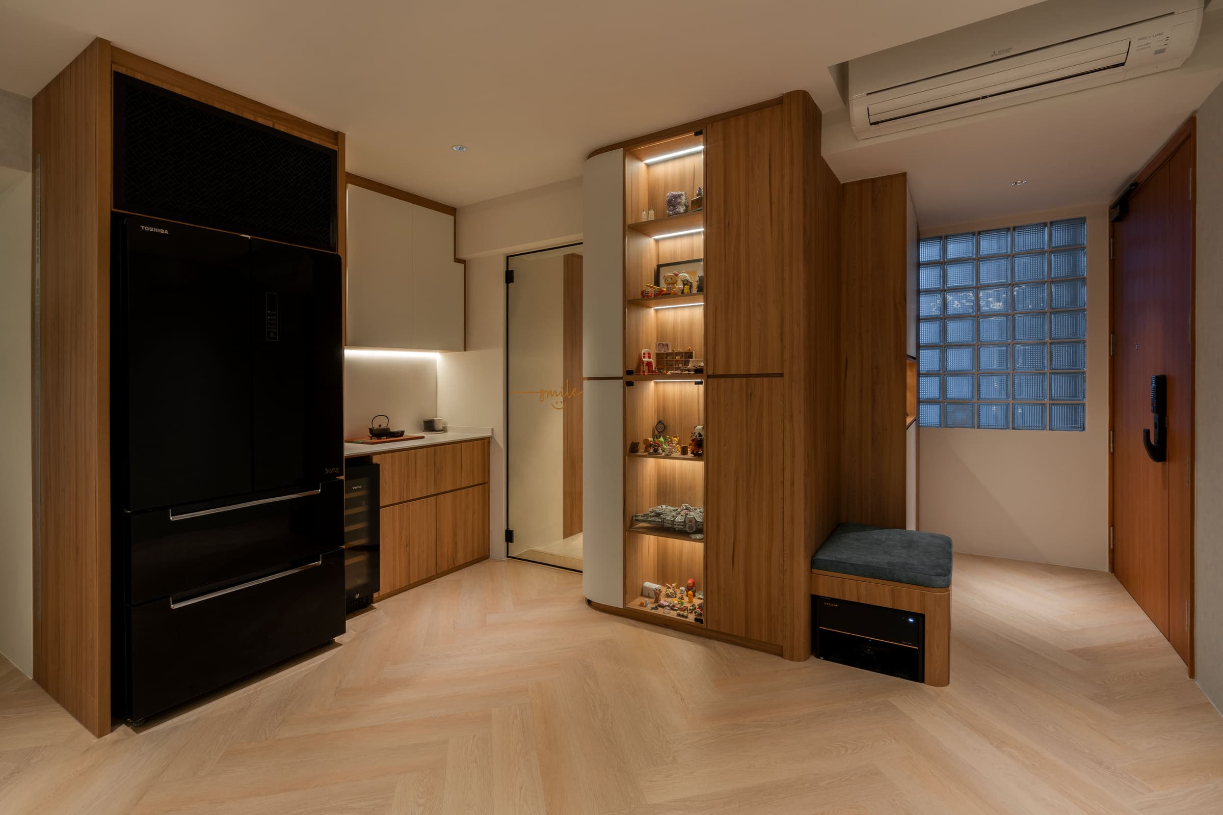 Entry and kitchen, with a lit display cabinet and concealed strips under the wall units.